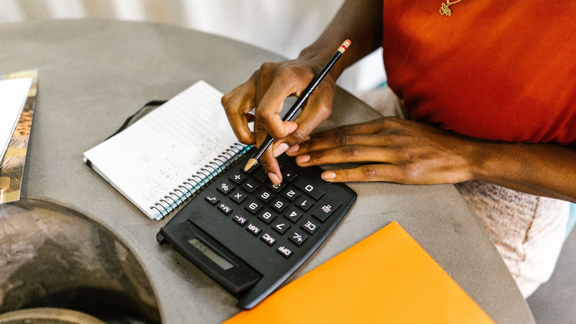 An African American woman using a calculator and notepad for budgeting.