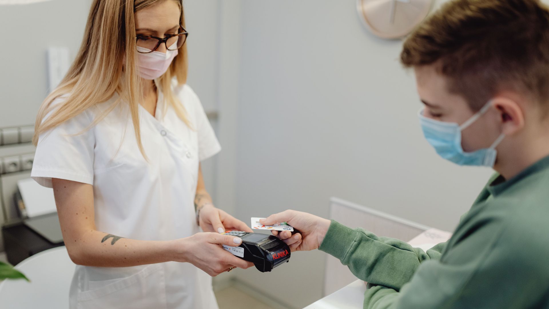 A healthcare professional processes a patient's card payment at the clinic reception.
