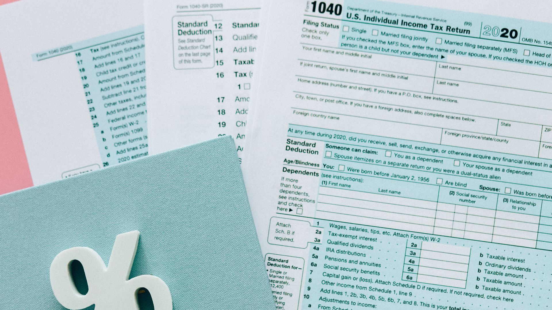 Tax documents with a percentage symbol on a pink and blue desk setup, emphasizing finance.