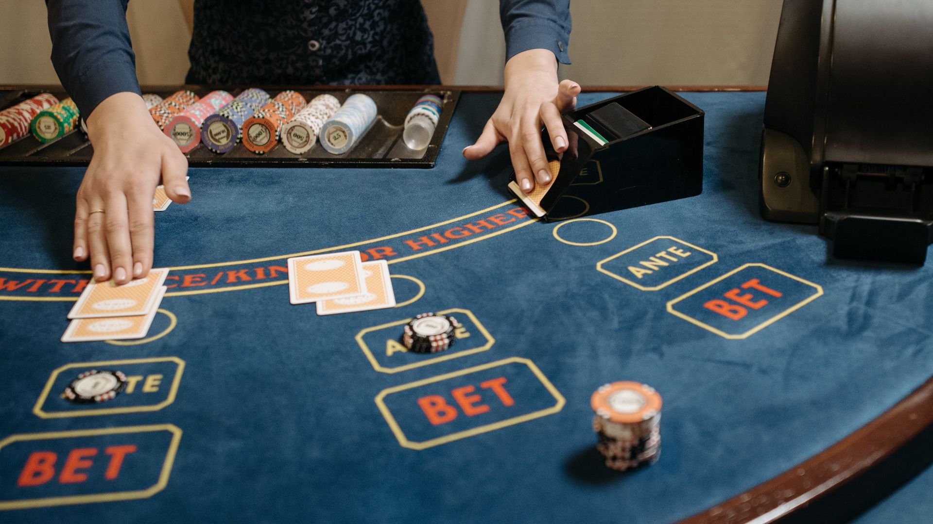 Casino dealer organizing cards and chips on a gaming table during a game.