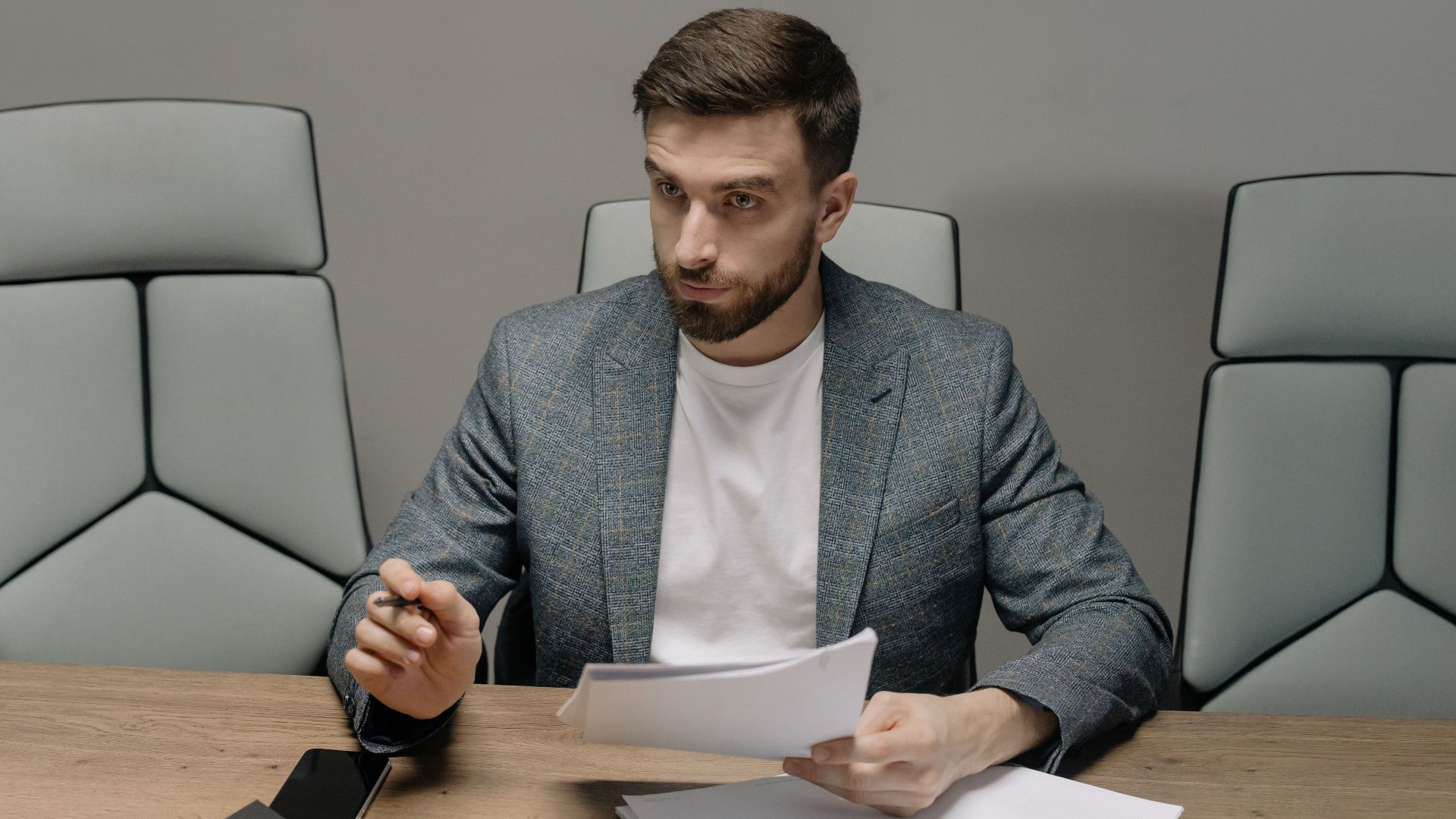 Professional businessman in a suit holding documents during a meeting in an office setting.