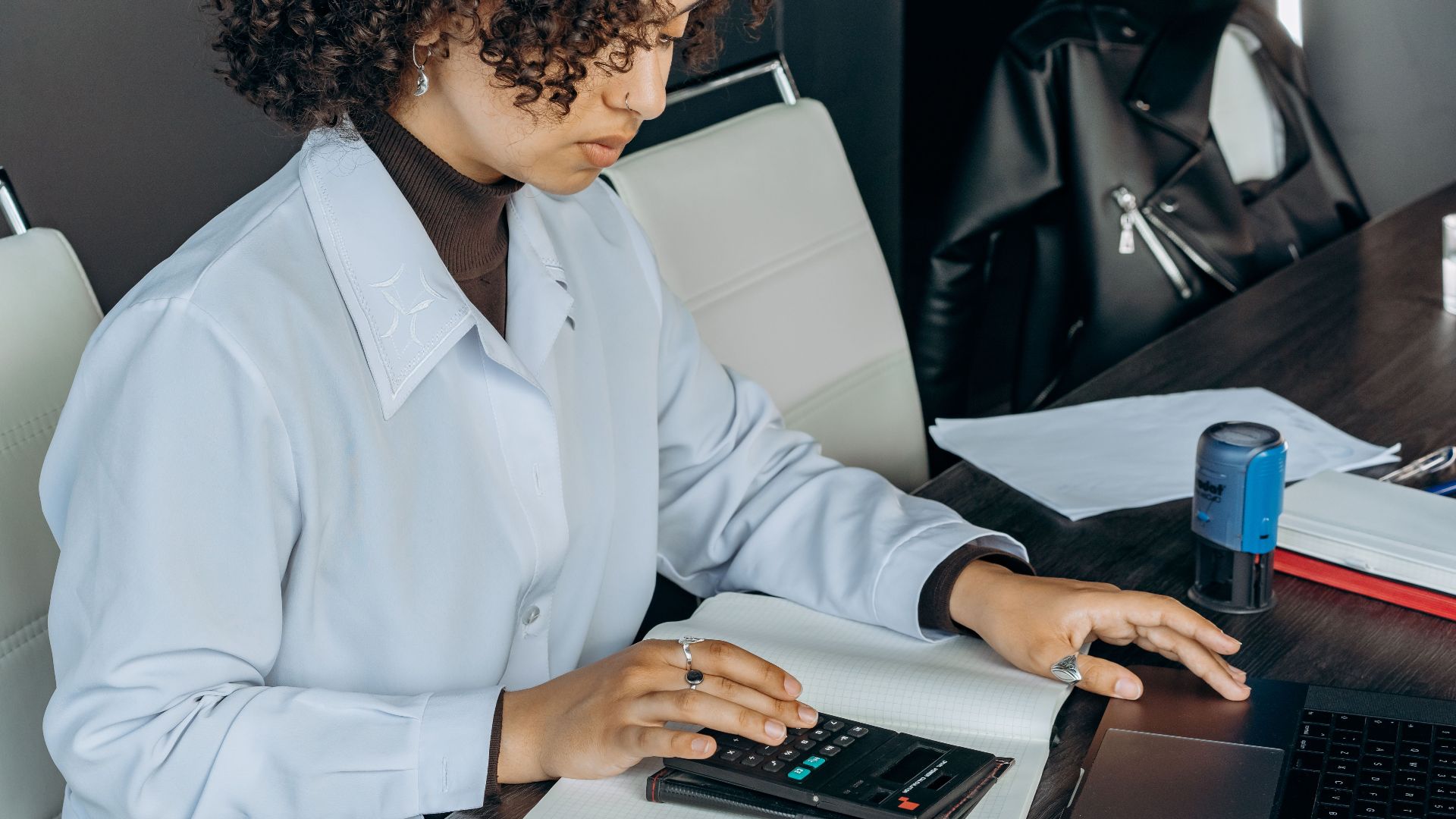 Young woman in office using a calculator for financial calculations.