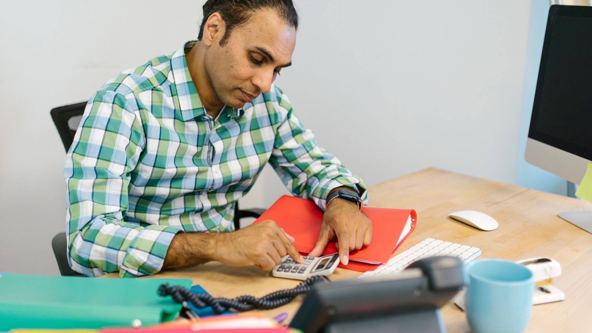 Man engaged in focused calculation work in an office environment.