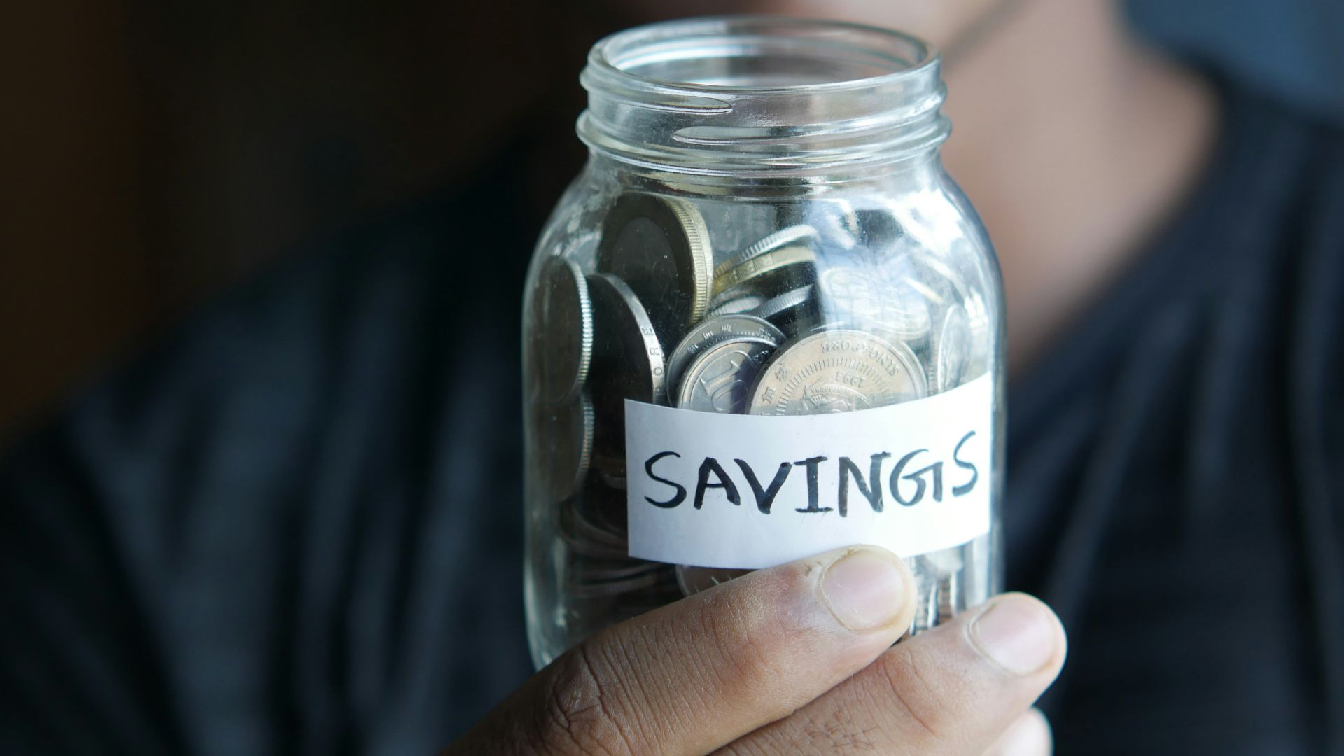 a man holding a jar with a savings label on it