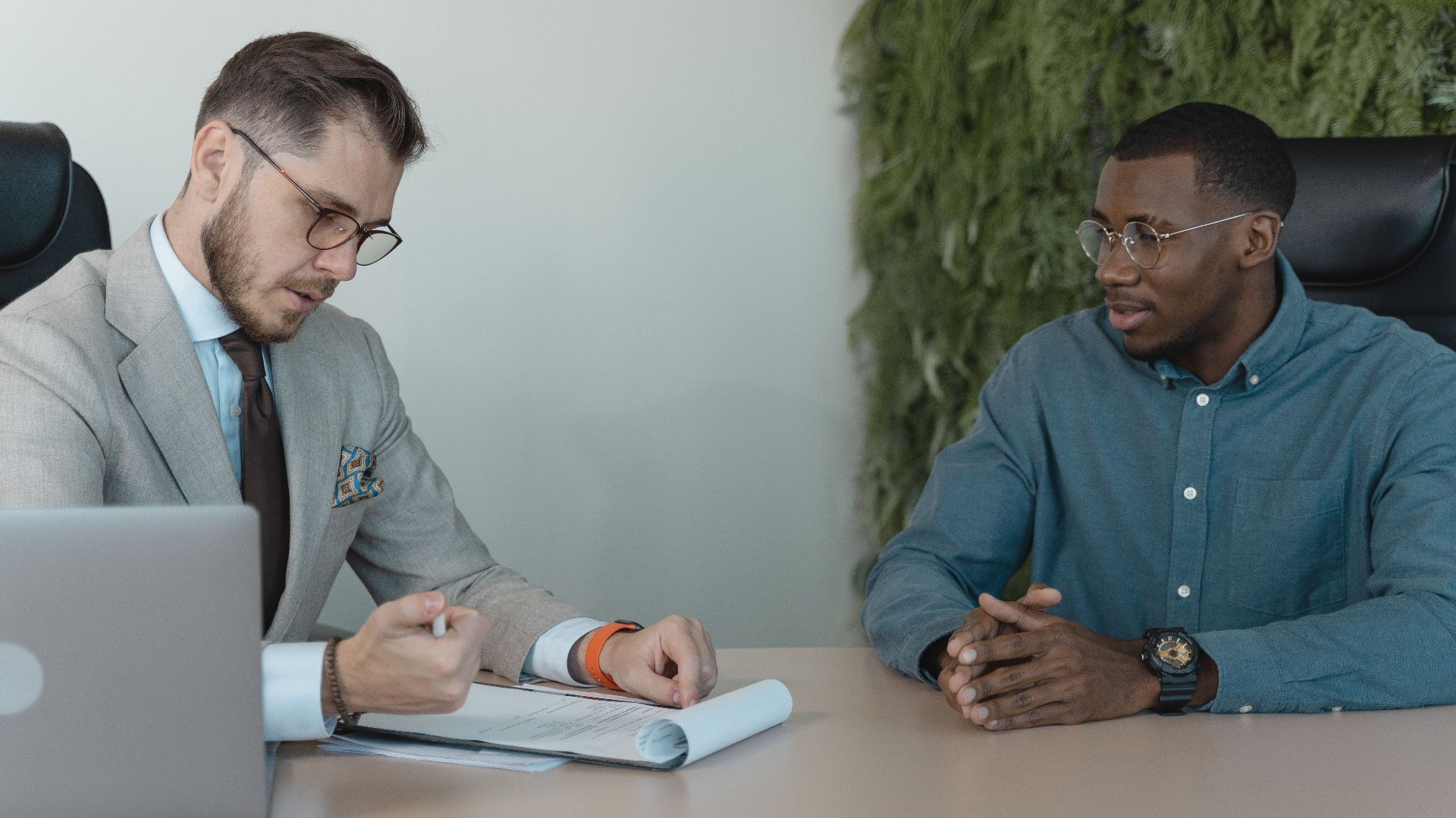 A professional job interview between two men in a modern office environment.