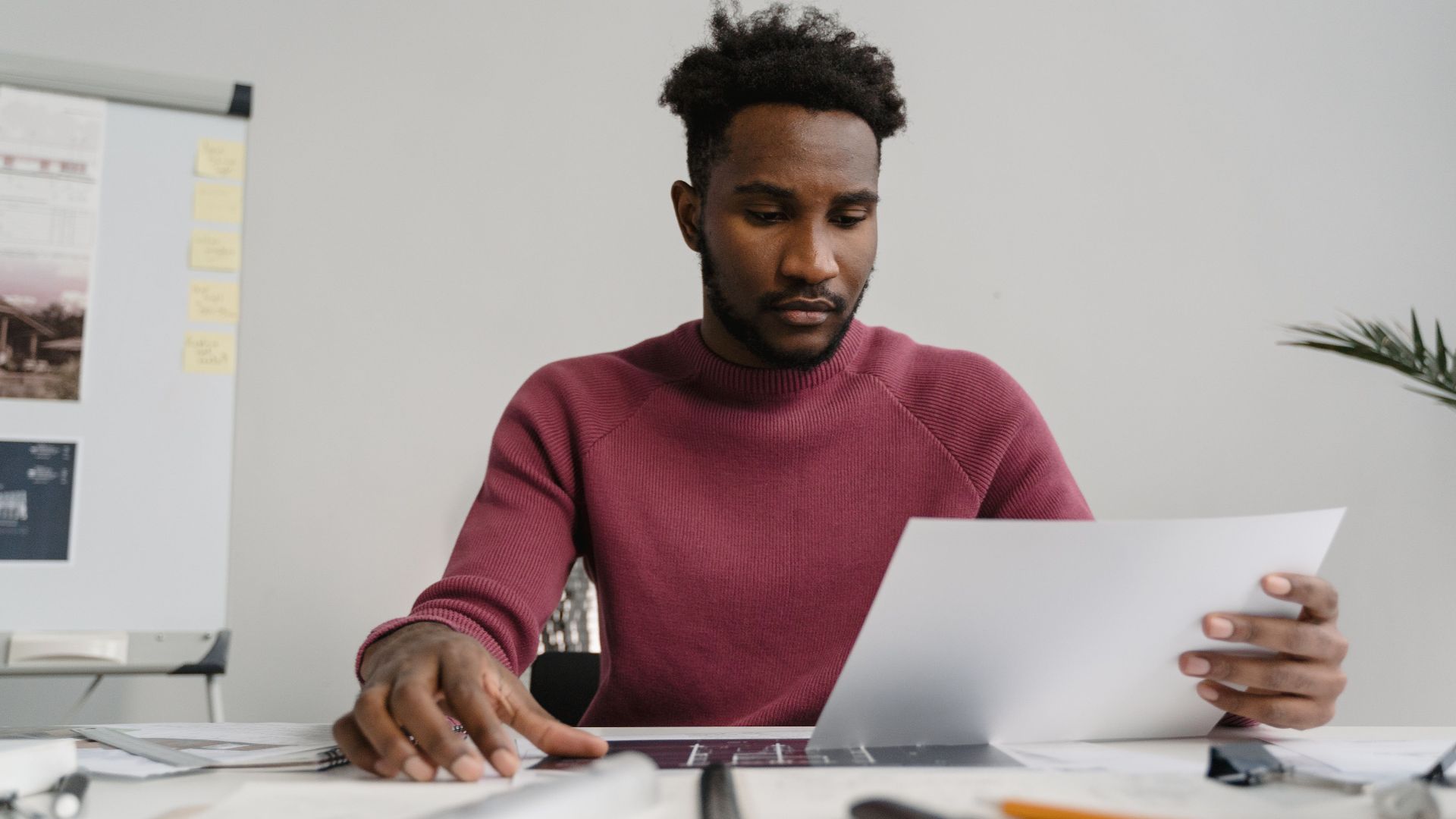 A man in a workspace analyzing a white document attentively. Modern office environment.