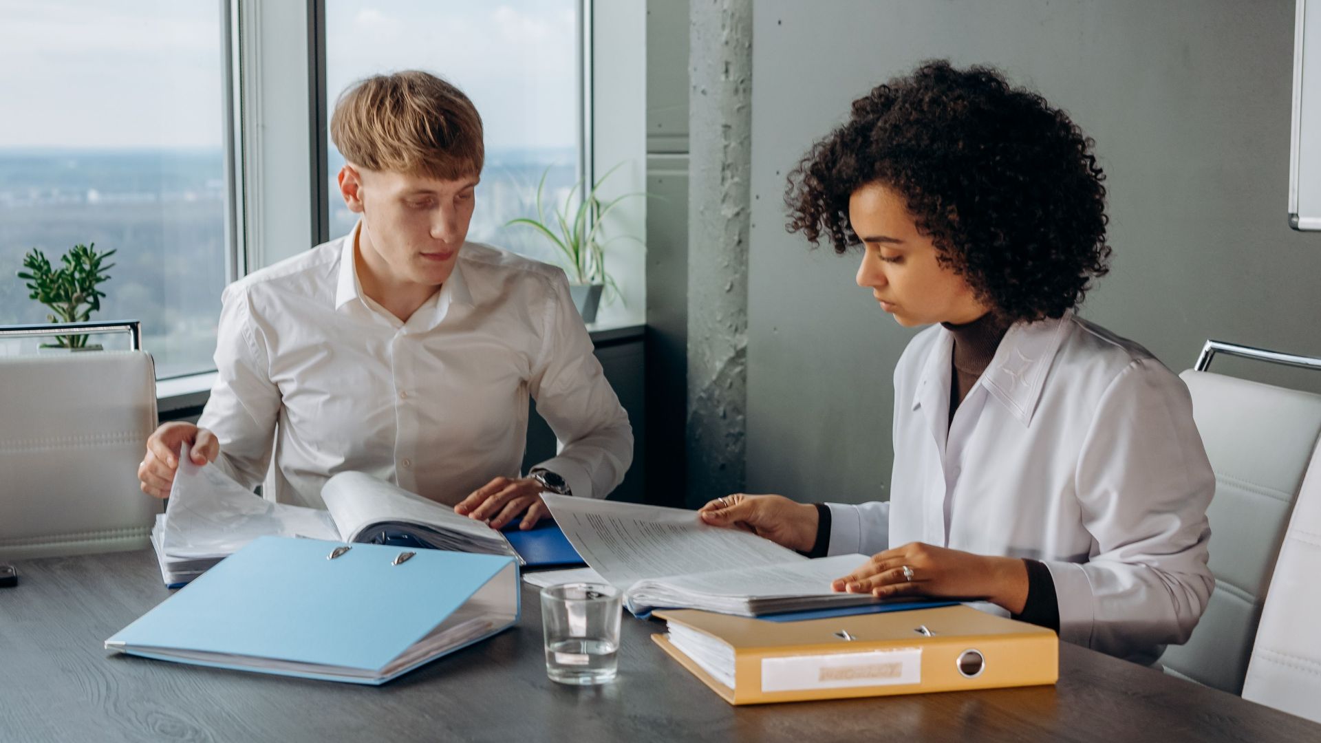 Two business colleagues analyzing financial reports at a desk in a modern office environment.