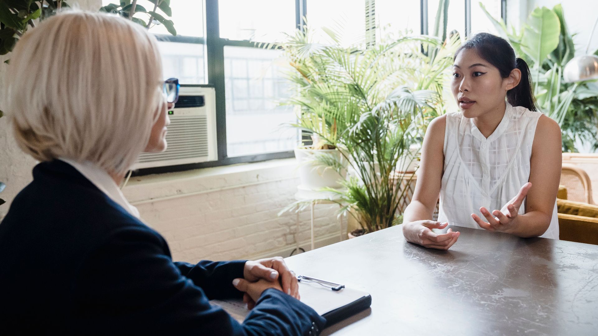 Two women engaged in a professional consultation at a modern indoor office setting.