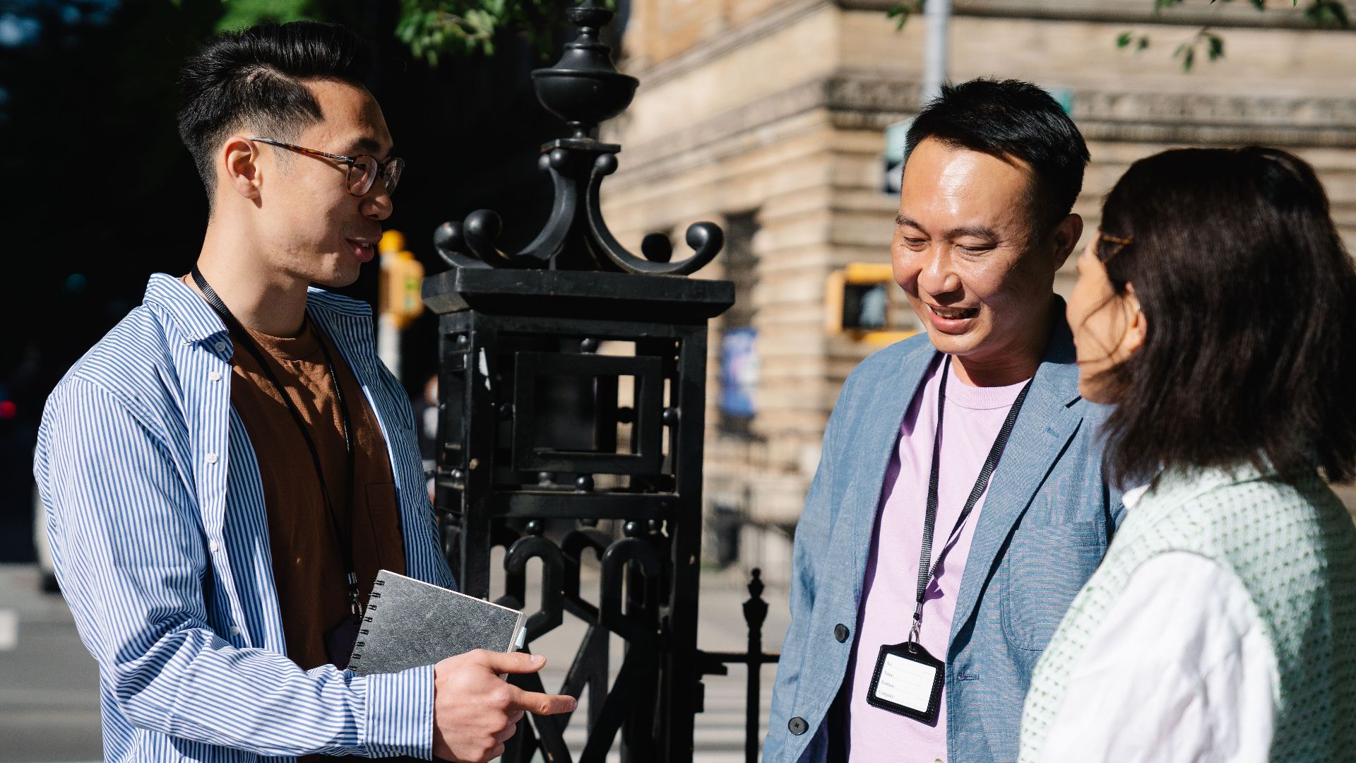 A group of colleagues engaging in a business discussion outdoors on a sunny day.