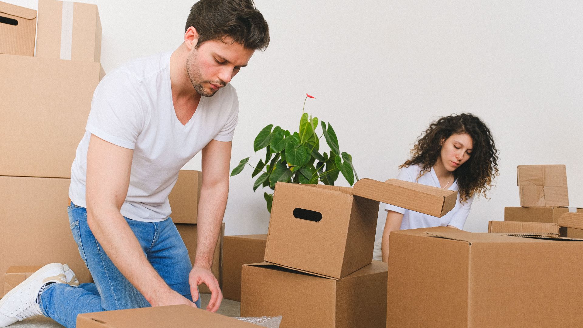 A young couple unpacks boxes in their new home, creating a cozy space together.