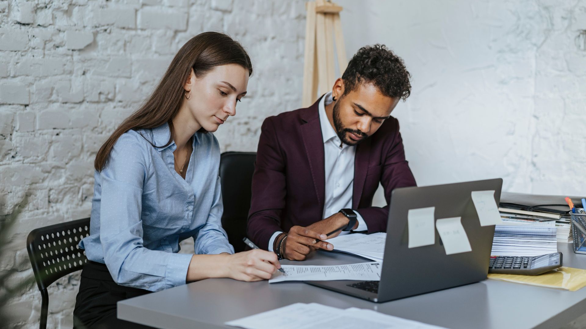 Two professionals working together at a desk in a modern office environment.