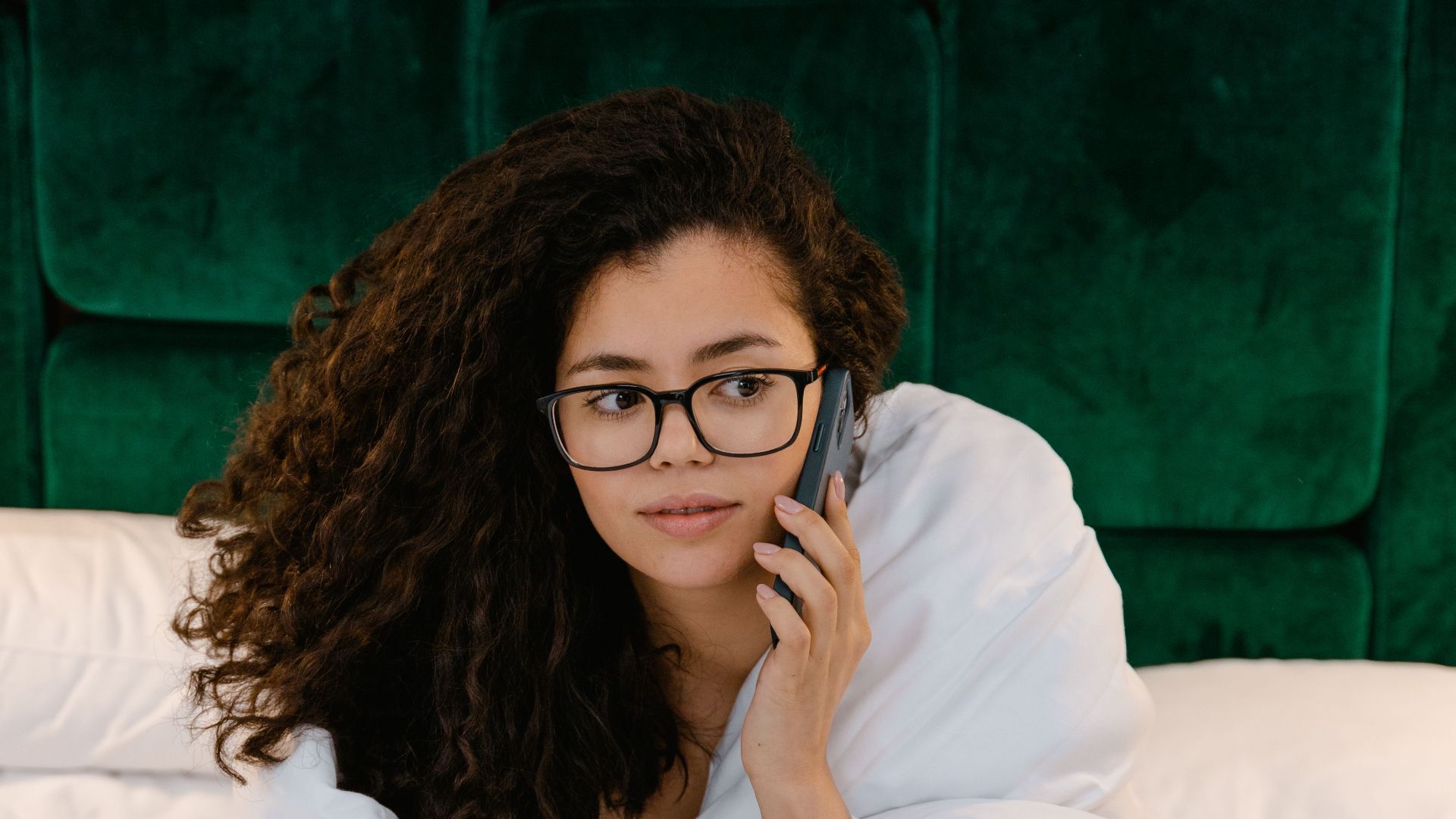 Casual morning call in bed with a woman wrapped in a blanket.