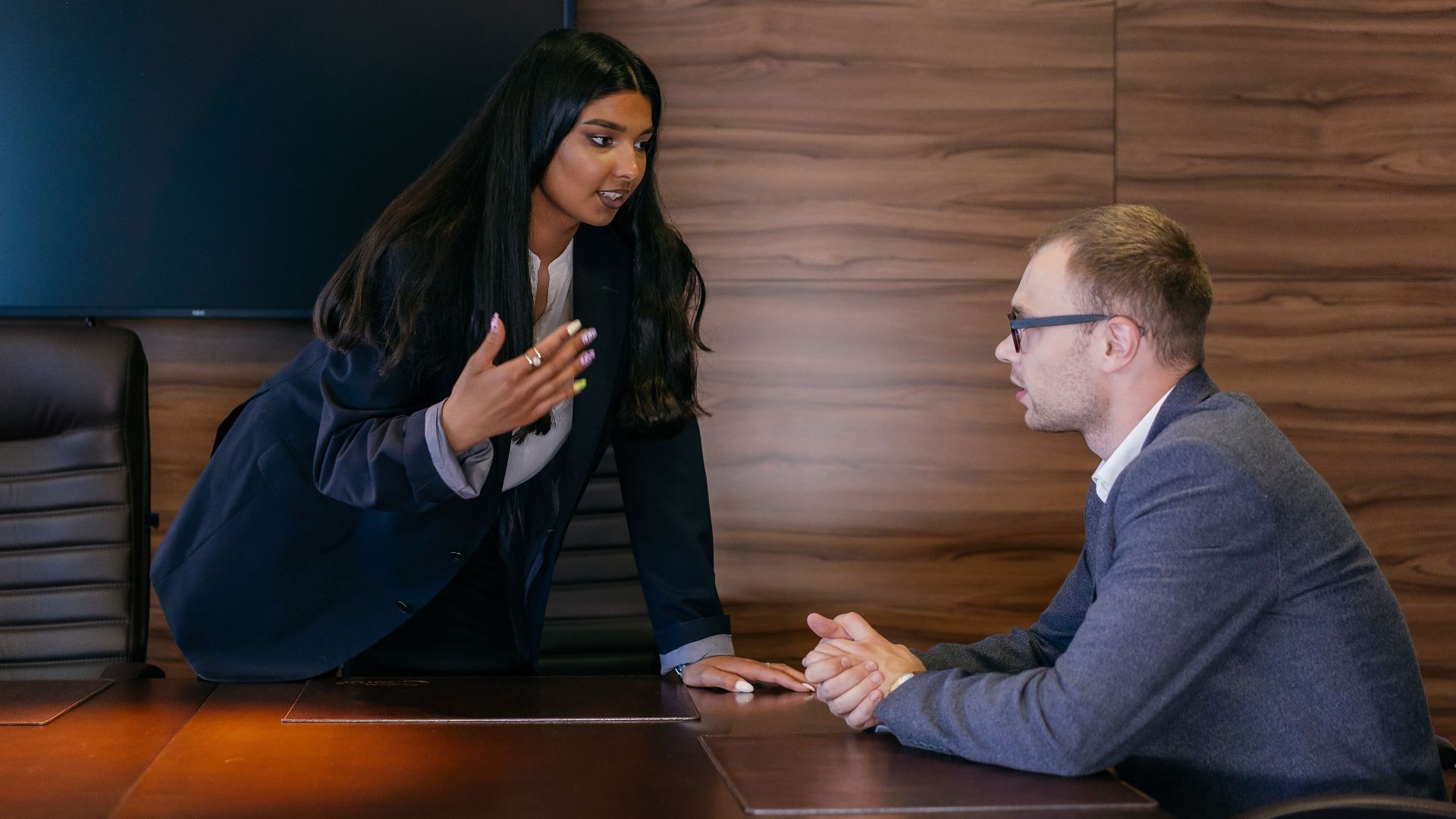 Two professionals having a discussion in a sleek conference room.