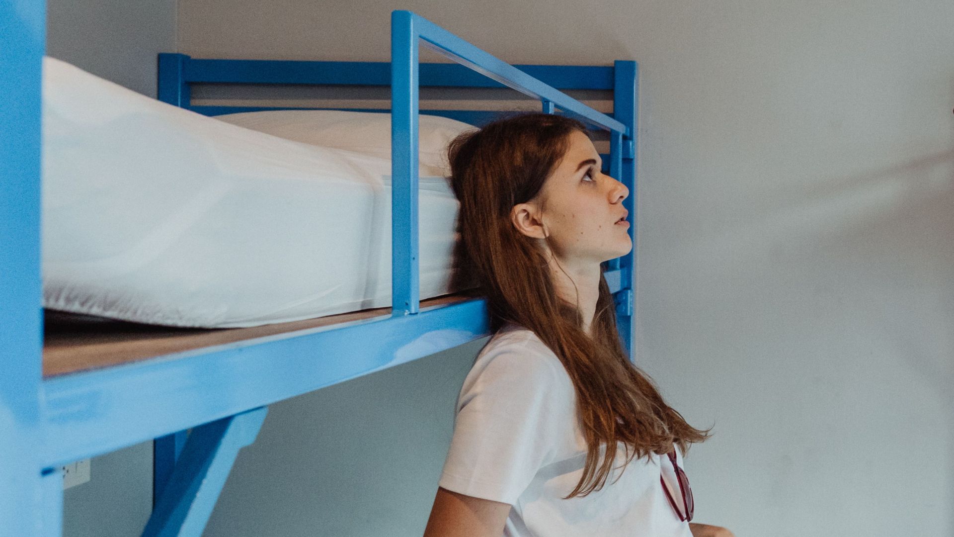 Two young women engaging in conversation in a casual hostel setting with blue bunk beds.