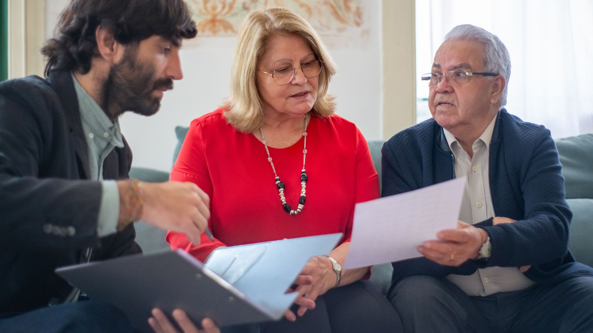Senior couple consulting with a professional advisor, discussing documents indoors.