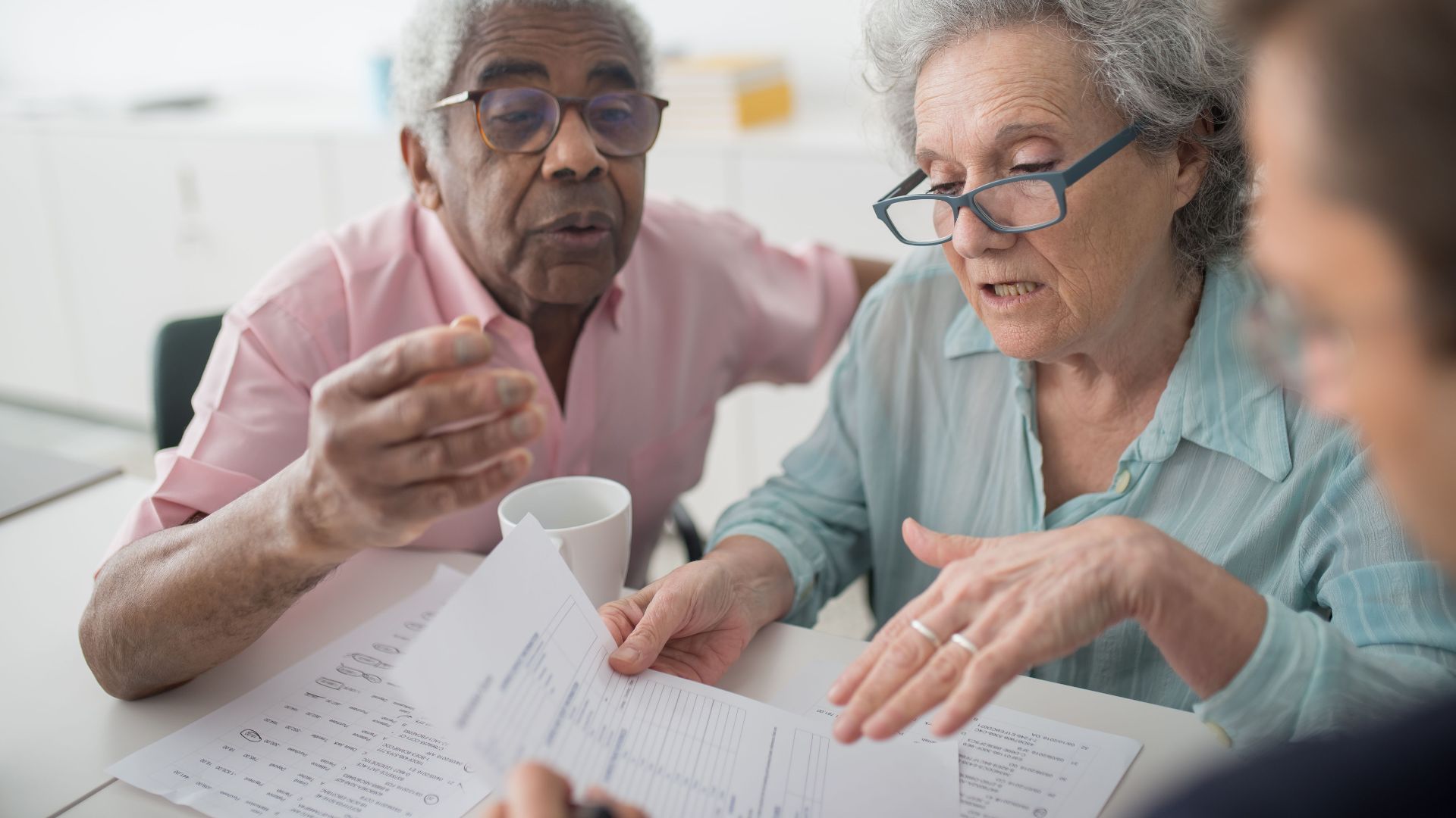 Elderly couple discussing financial documents with a consultant in an office setting.