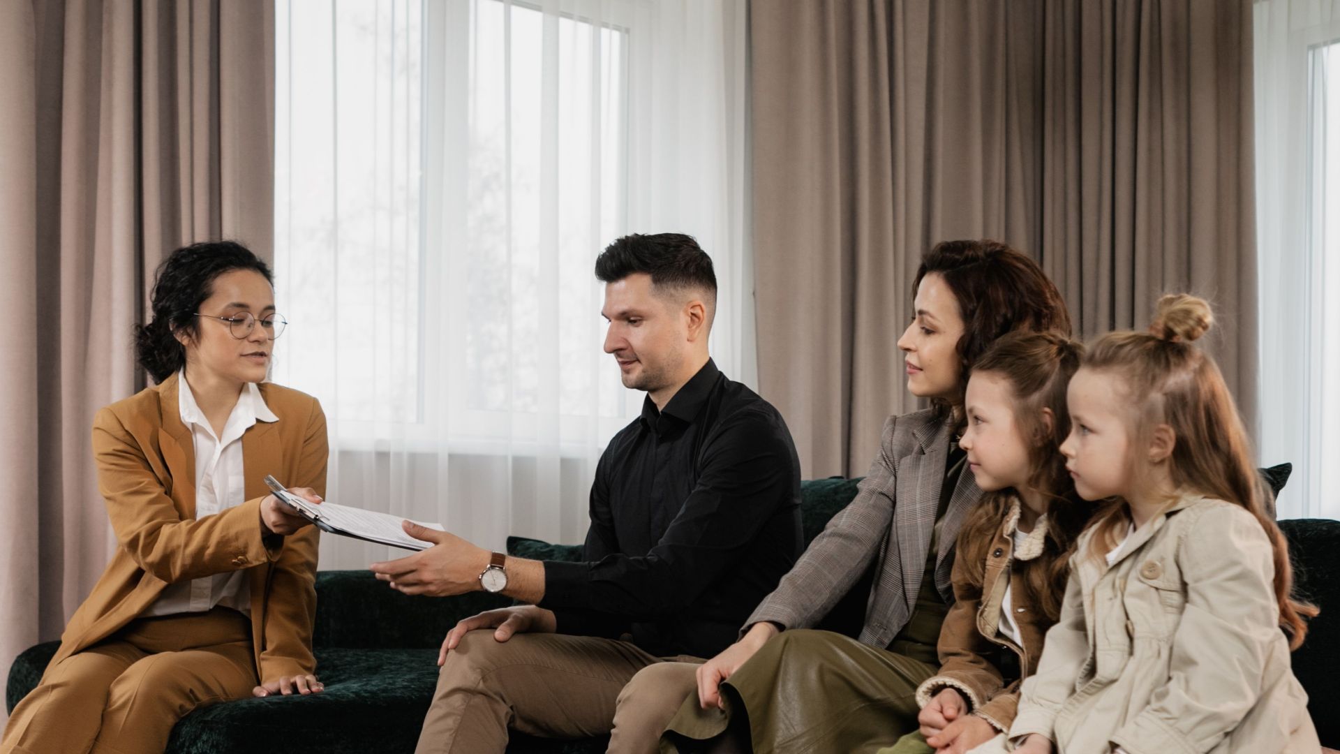 A family meets with a real estate agent in a stylish living room, reviewing documents for a potential home purchase.