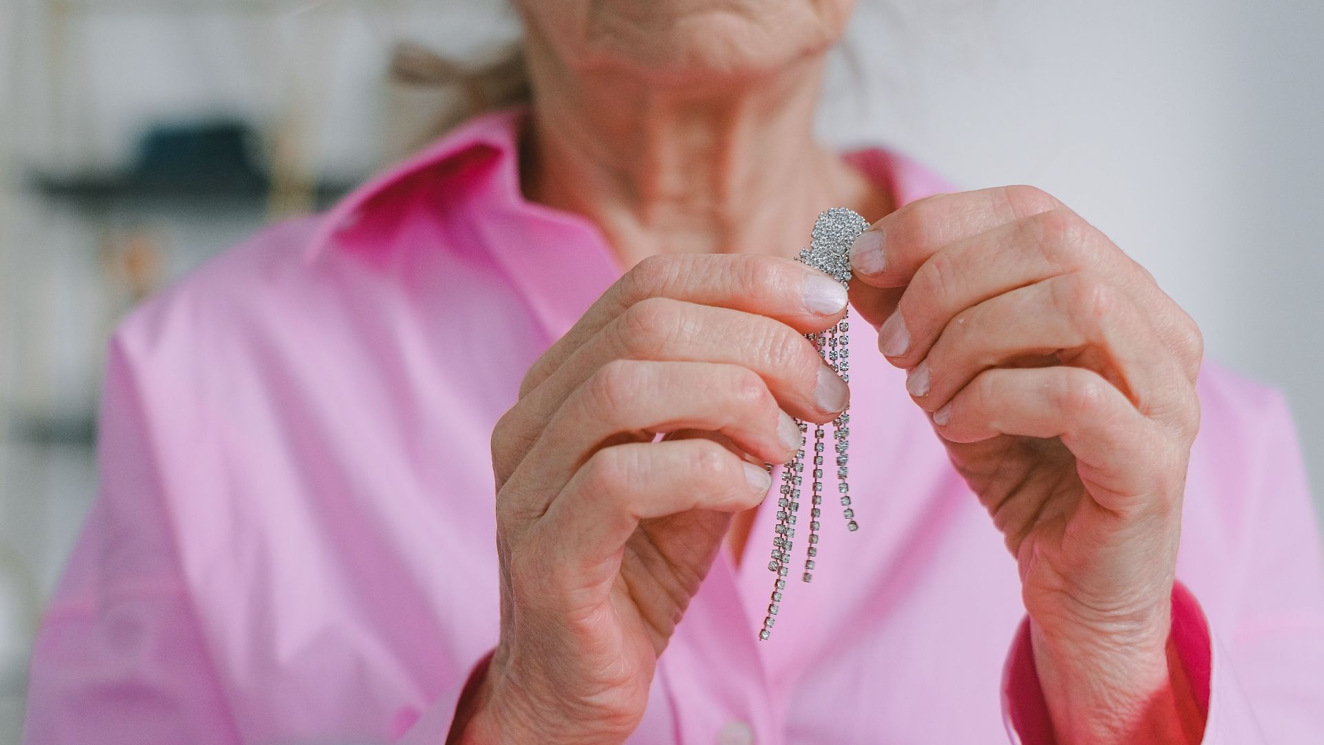 Senior woman holds sparkling jewelry, highlighting elegance in daily life.