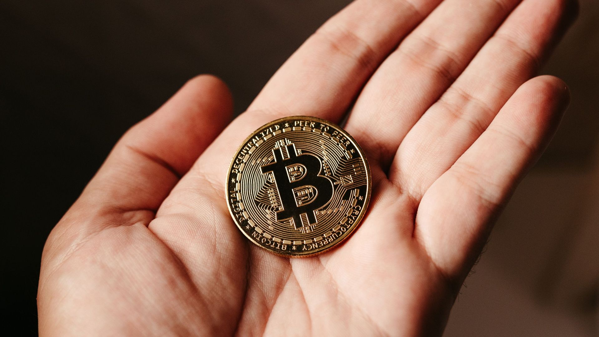 Close-up of a hand holding a Bitcoin coin, illustrating cryptocurrency concept.