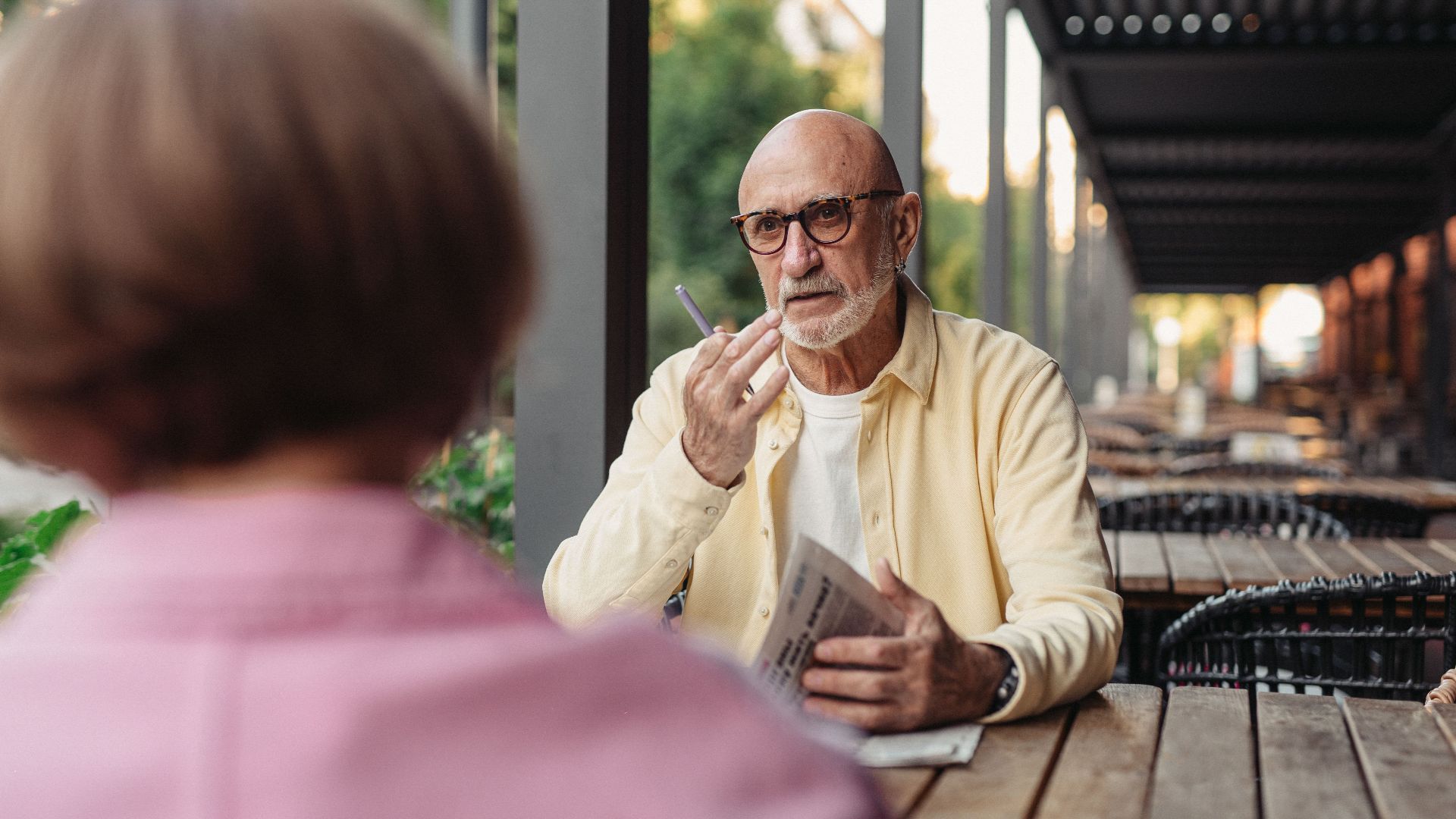Elderly couple conversing at an outdoor cafe, enjoying a peaceful moment together.