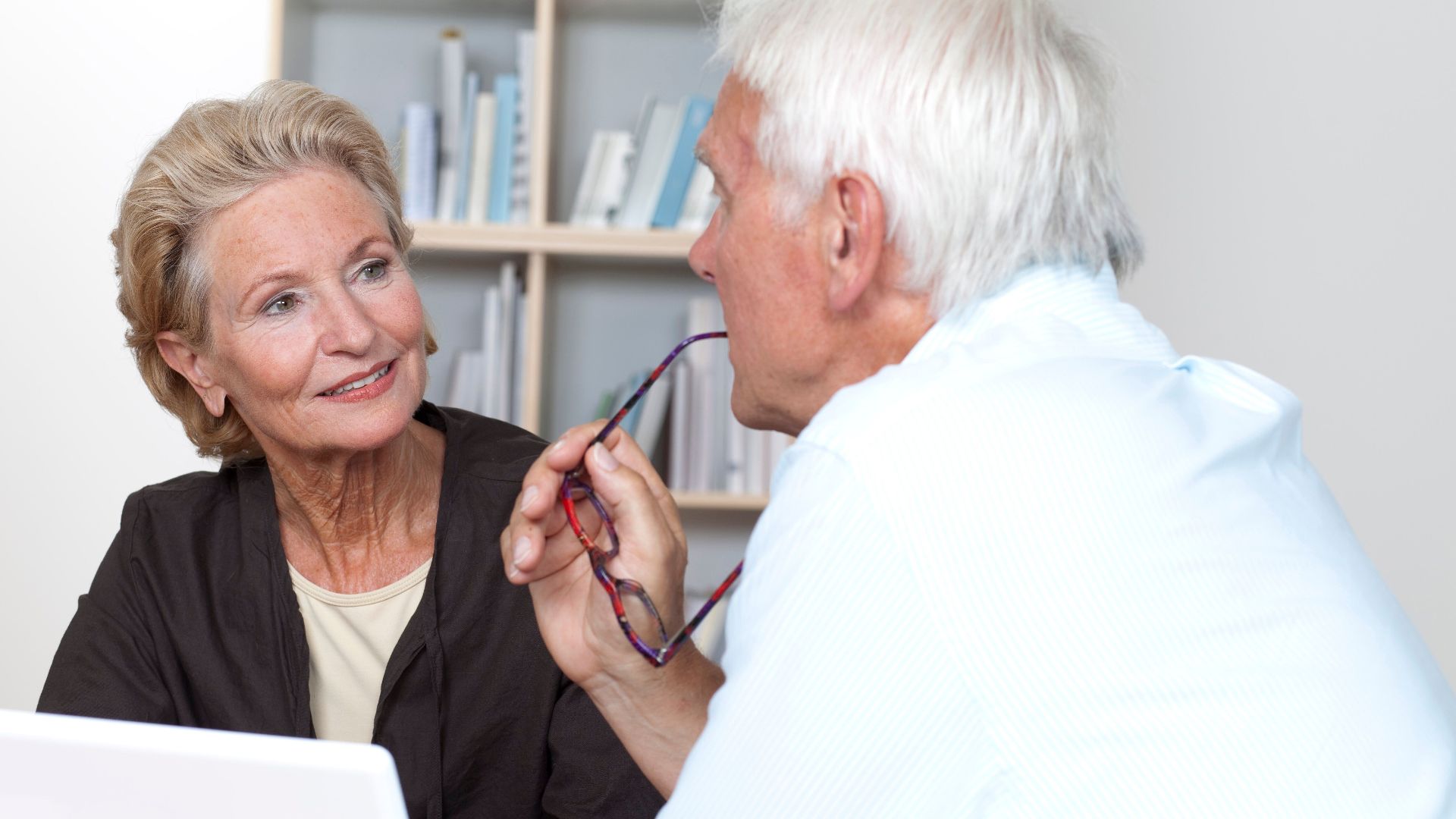 Elderly couple sharing a meaningful conversation indoors with affection and understanding.