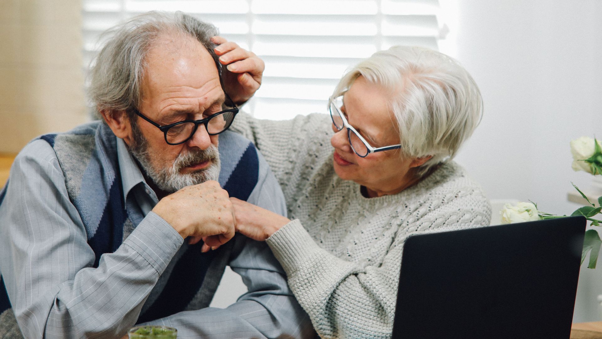 An elderly couple at home engaging with technology on a laptop in a modern setting.