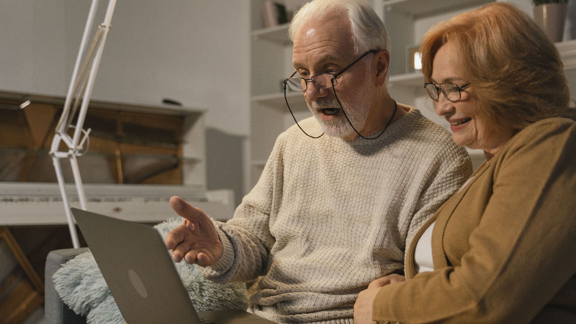 Senior couple smiling and gesturing during a video call on a laptop at home.