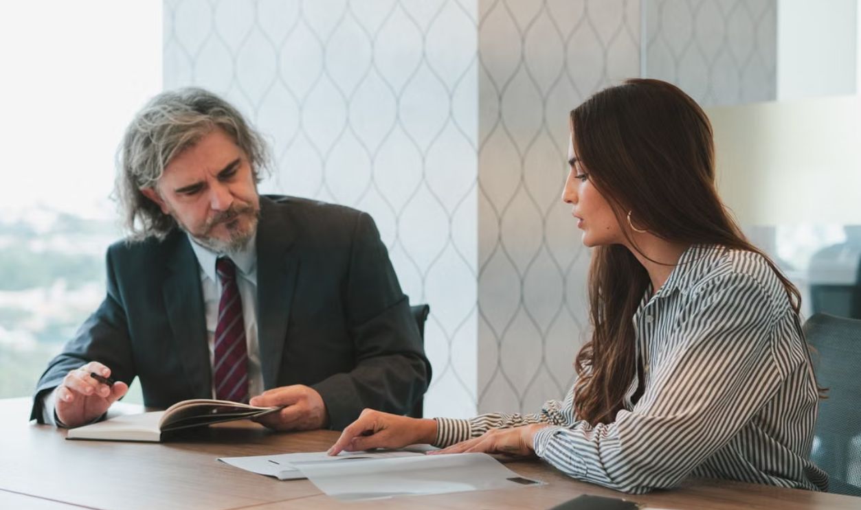 Professional business meeting in a modern office with two adults discussing documents