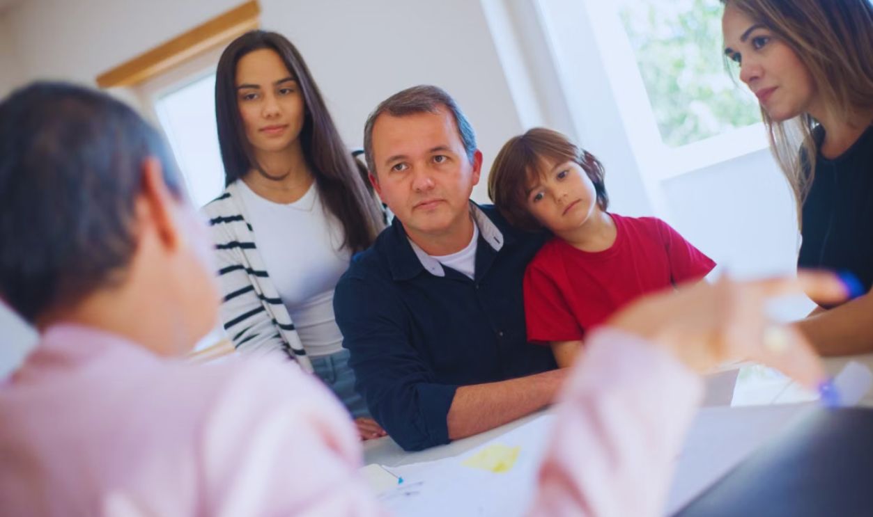 A family of four seeks advice from a professional during an indoor consultation in a bright room