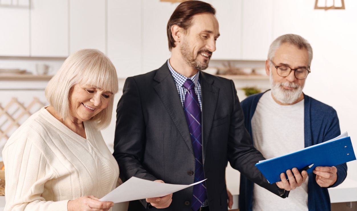 Cheerful lawyer demonstrating contract for elderly couple of clients