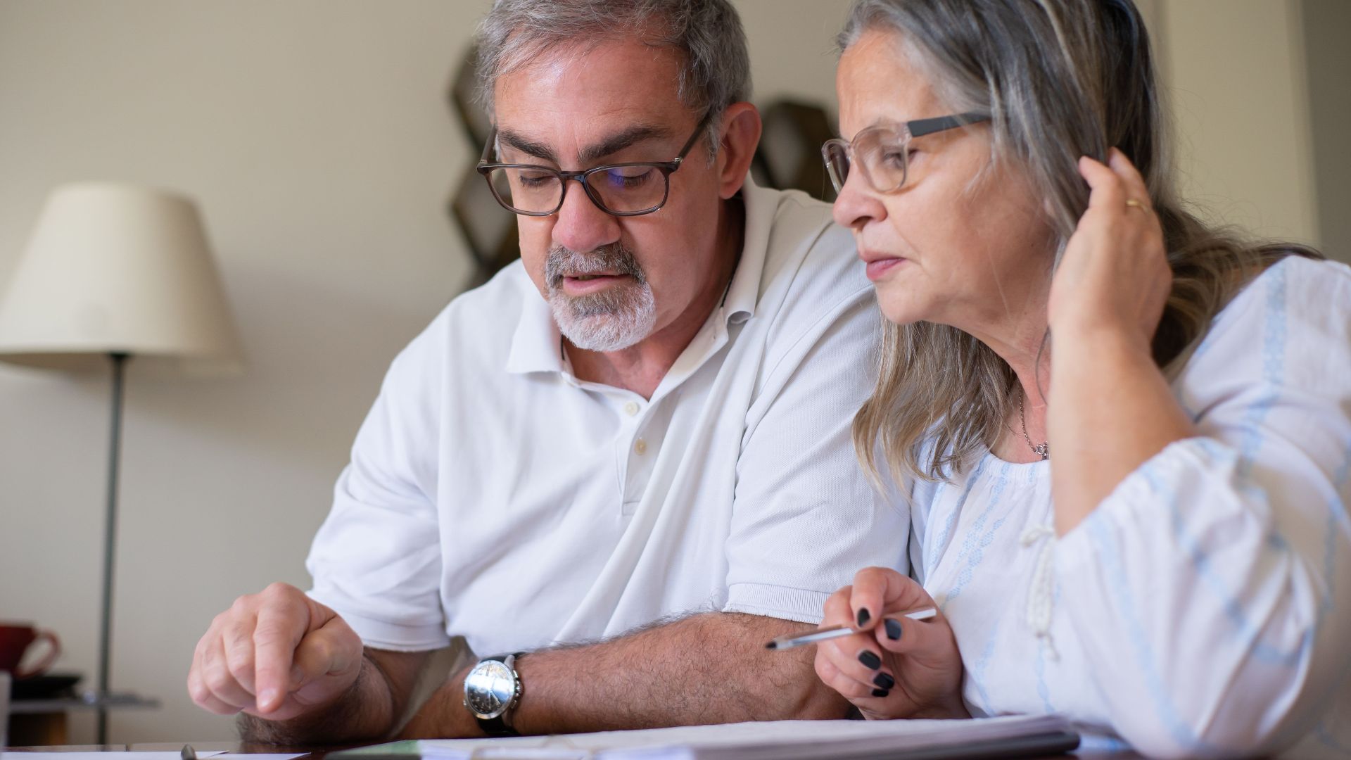 Elderly couple enjoying leisure time with crosswords at home, showcasing togetherness.
