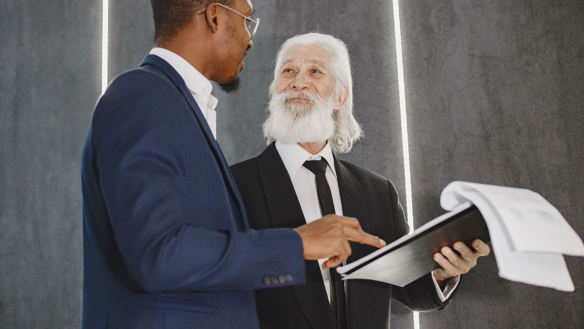 Two businessmen discussing documents in a modern office setting, highlighting professional diversity.