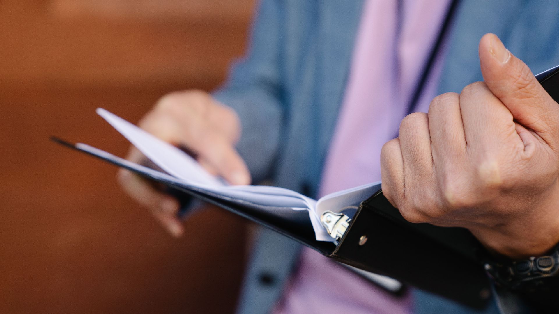 Person flipping through documents in a binder, showcasing organization and focus.