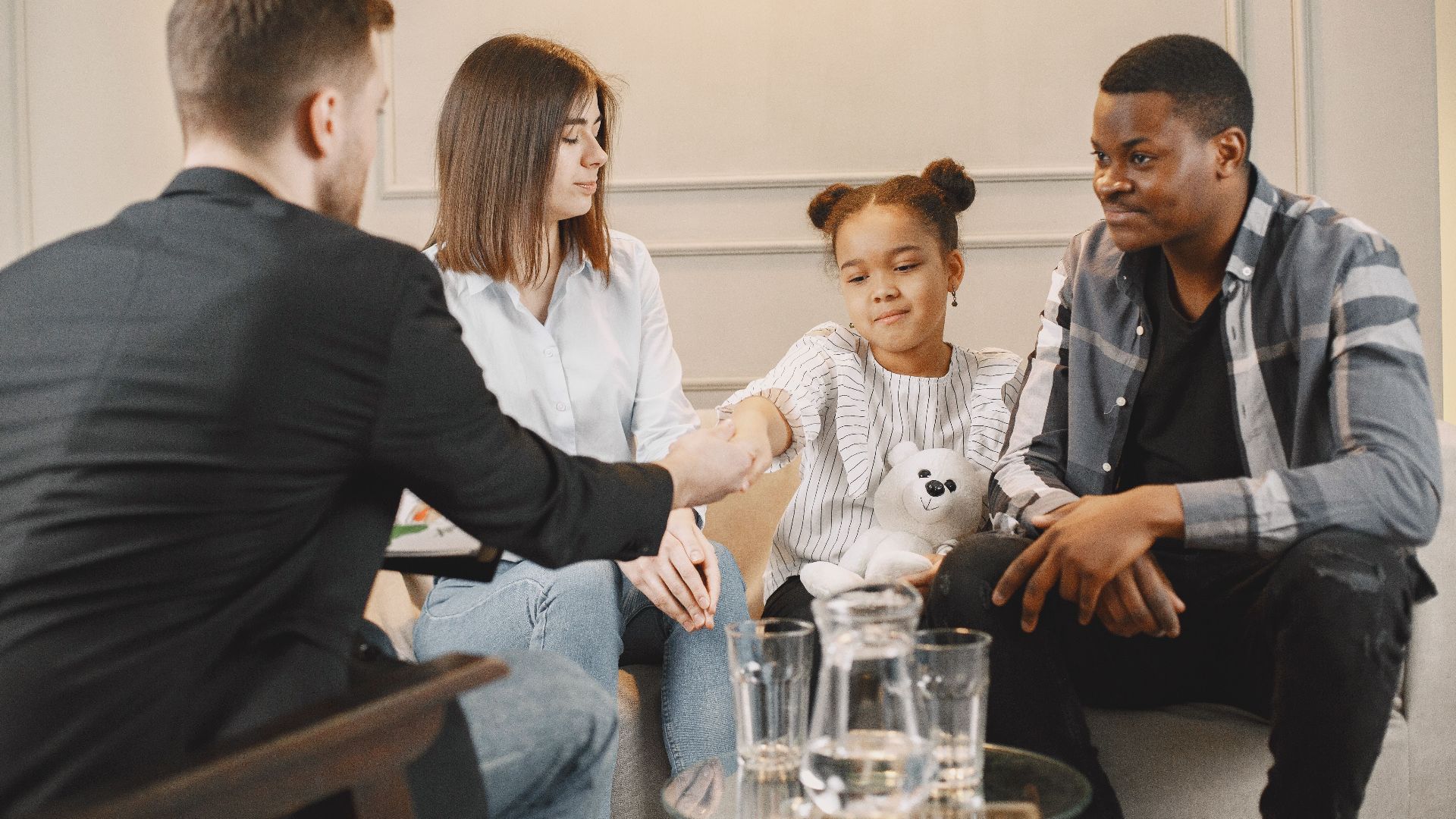 A family in a thoughtful counselling session with a professional in a modern setting.