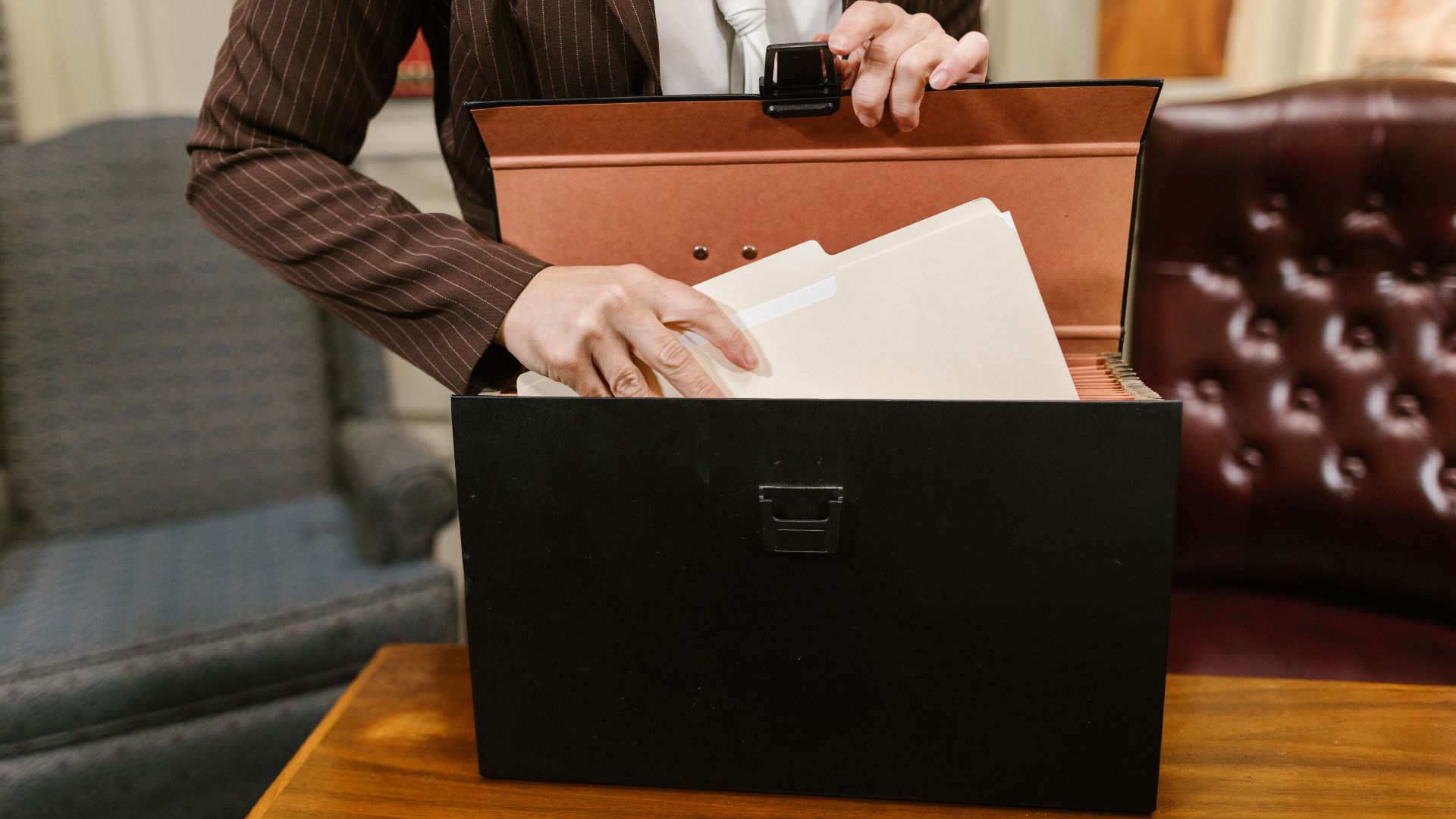 Close-up of a businesswoman organizing files in a black box in an office setting.