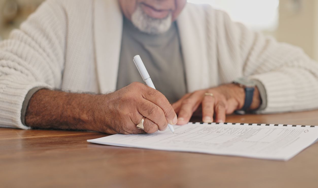 Home, writing and old man with documents, hands and folder for retirement plan, signature and form. Closeup, apartment and life insurance paperwork, legal agreement and pensioner with application