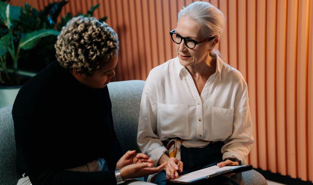 Two professional women engaged in a business discussion indoors with documents