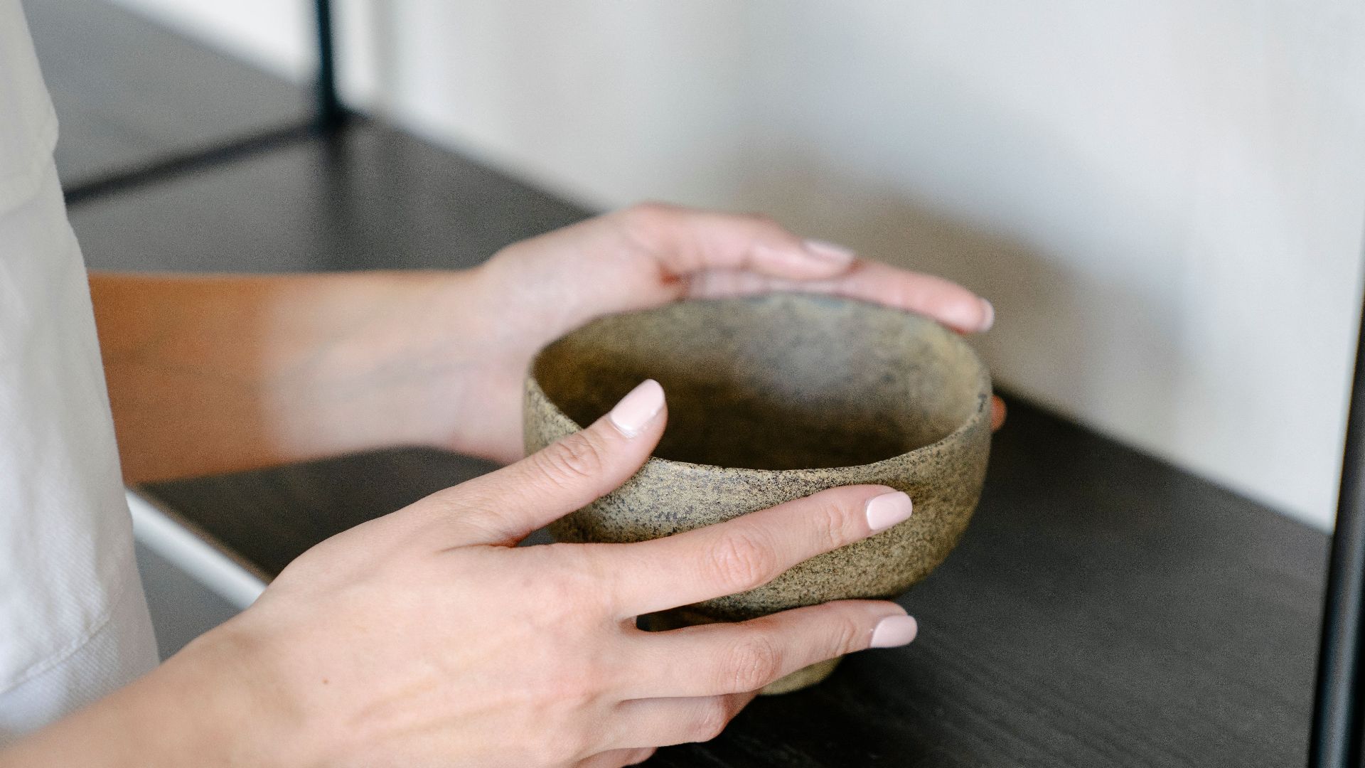 Minimalist close-up of hands holding a ceramic bowl in a peaceful setting.