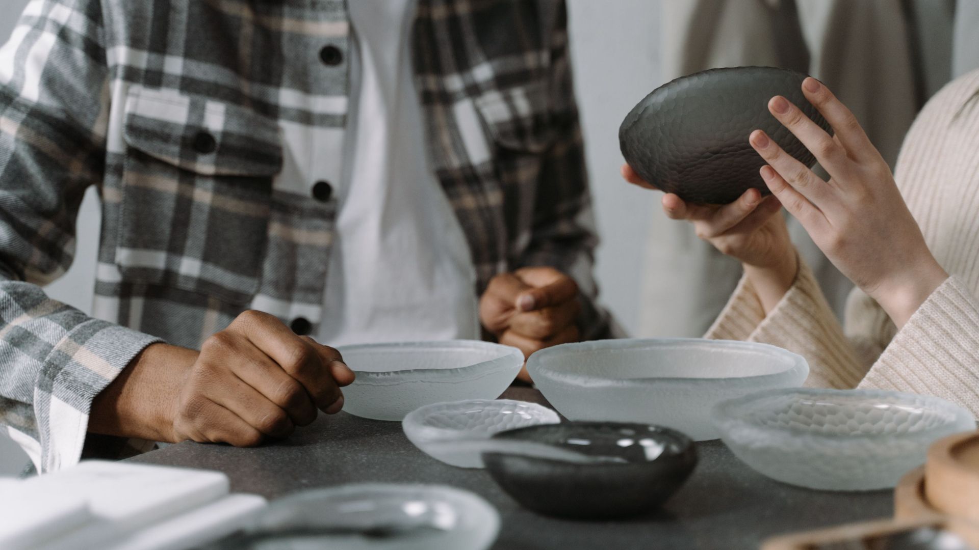 Close-up of two individuals examining ceramic bowls in a contemporary indoor setting.