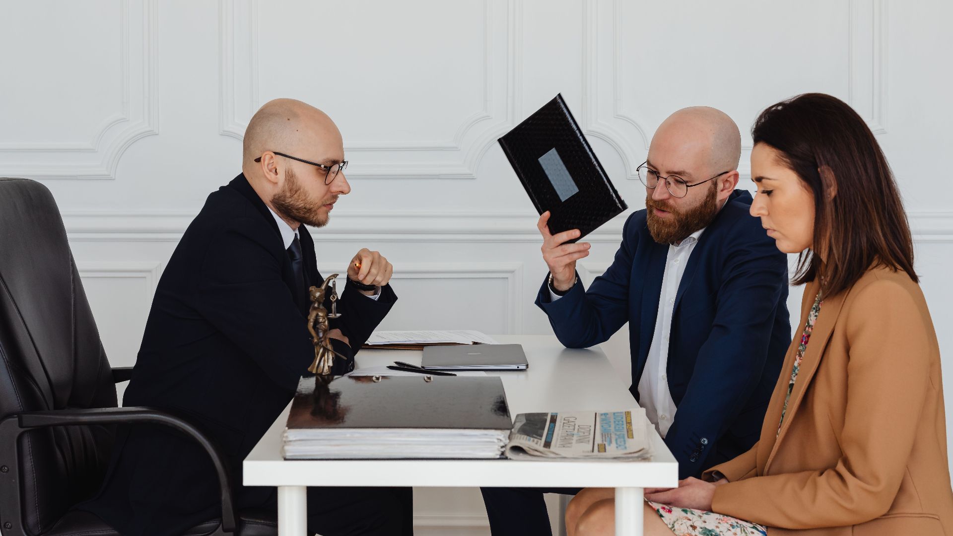 A couple in a legal consultation with a lawyer at an office desk.