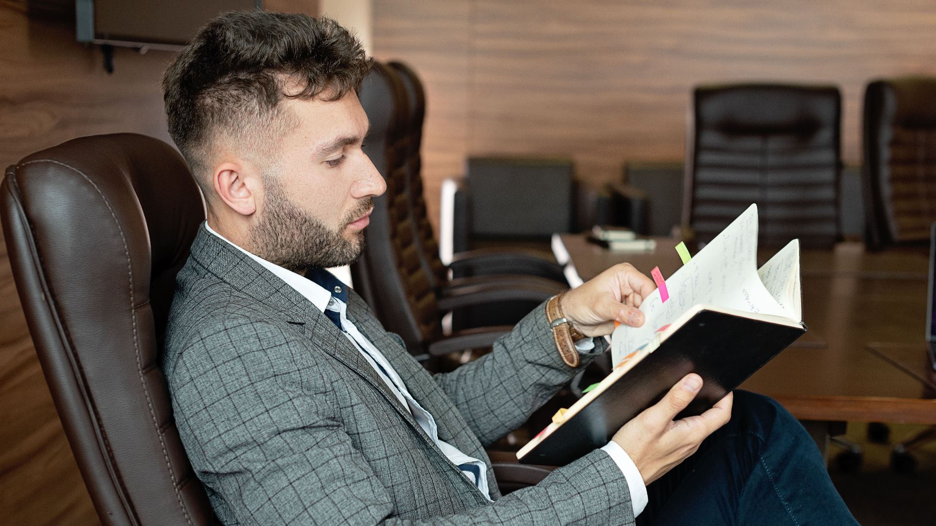 Professional businessman in formal attire reviewing notes in a modern office environment.