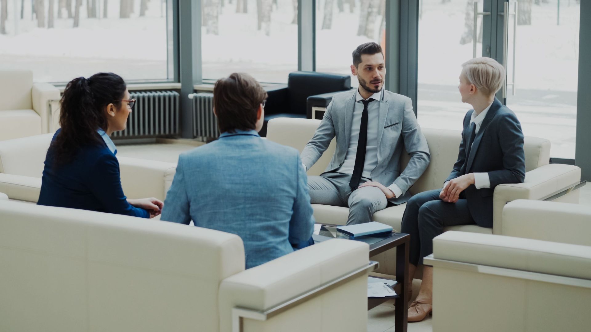 Group of professionals having a discussion in a bright office lounge.