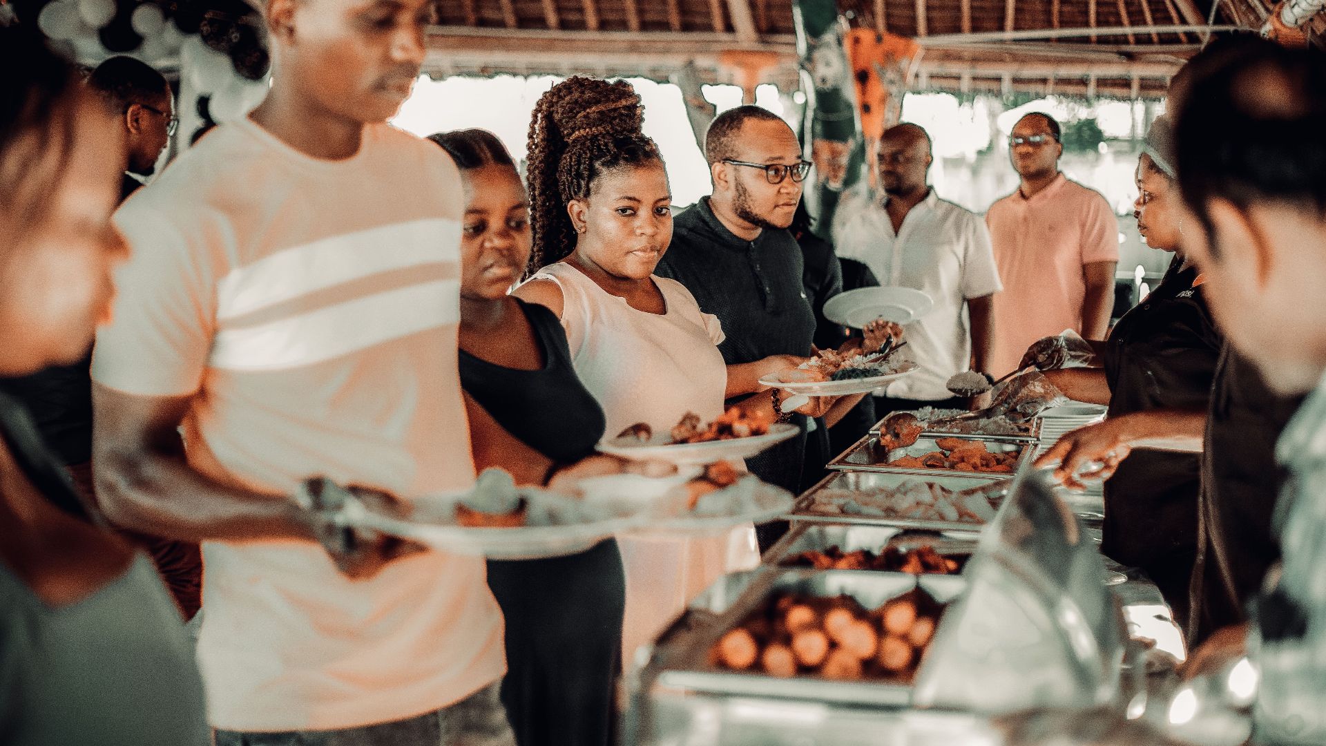 Group of African adults enjoying a festive buffet indoors with a lively atmosphere.