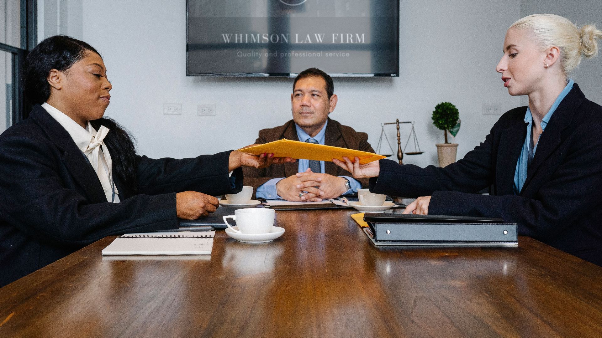Group of cheerful diverse colleagues discussing court decision at table with notepad and cup