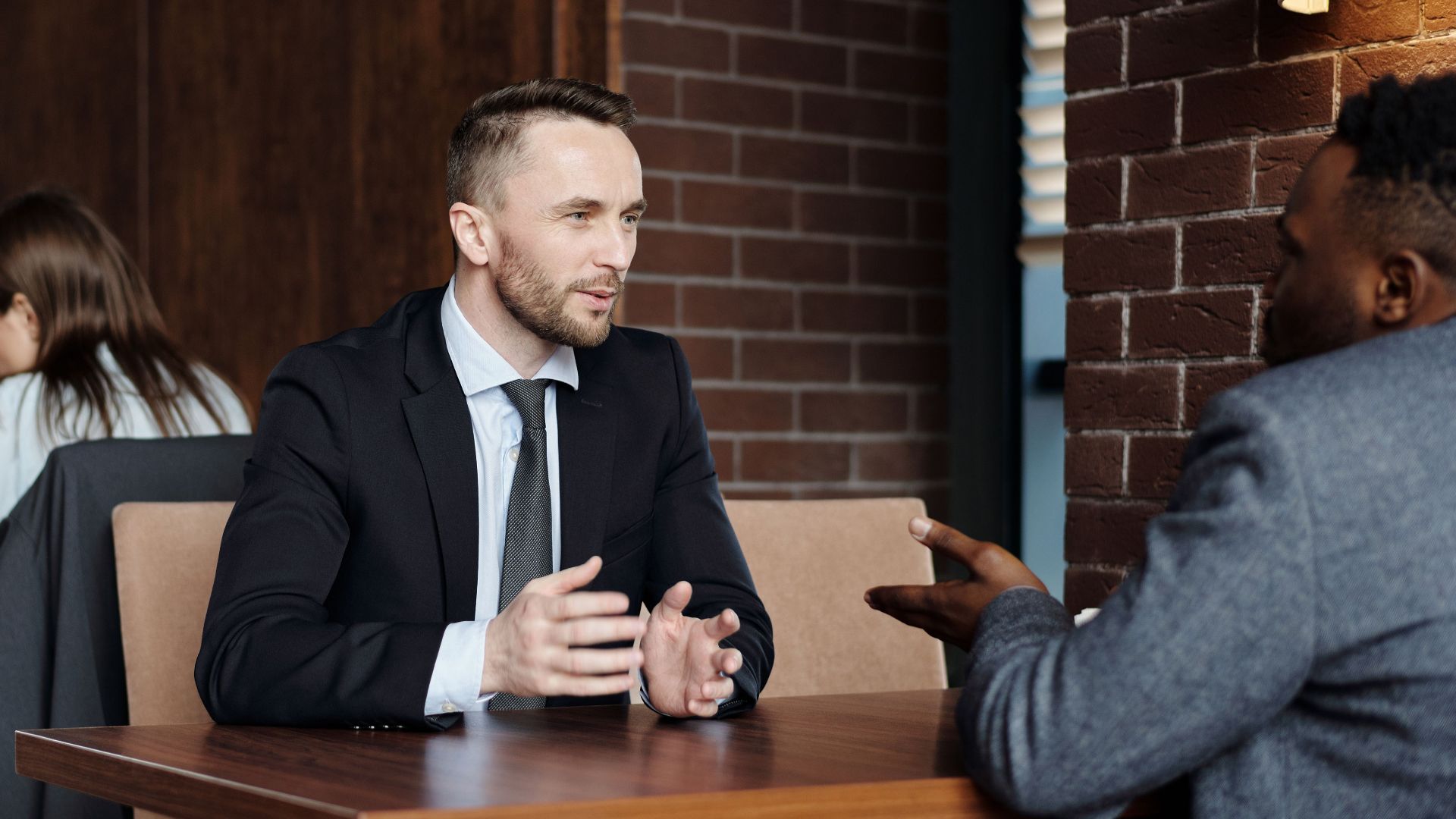 Businessmen engaged in a professional conversation in a stylish café setting.