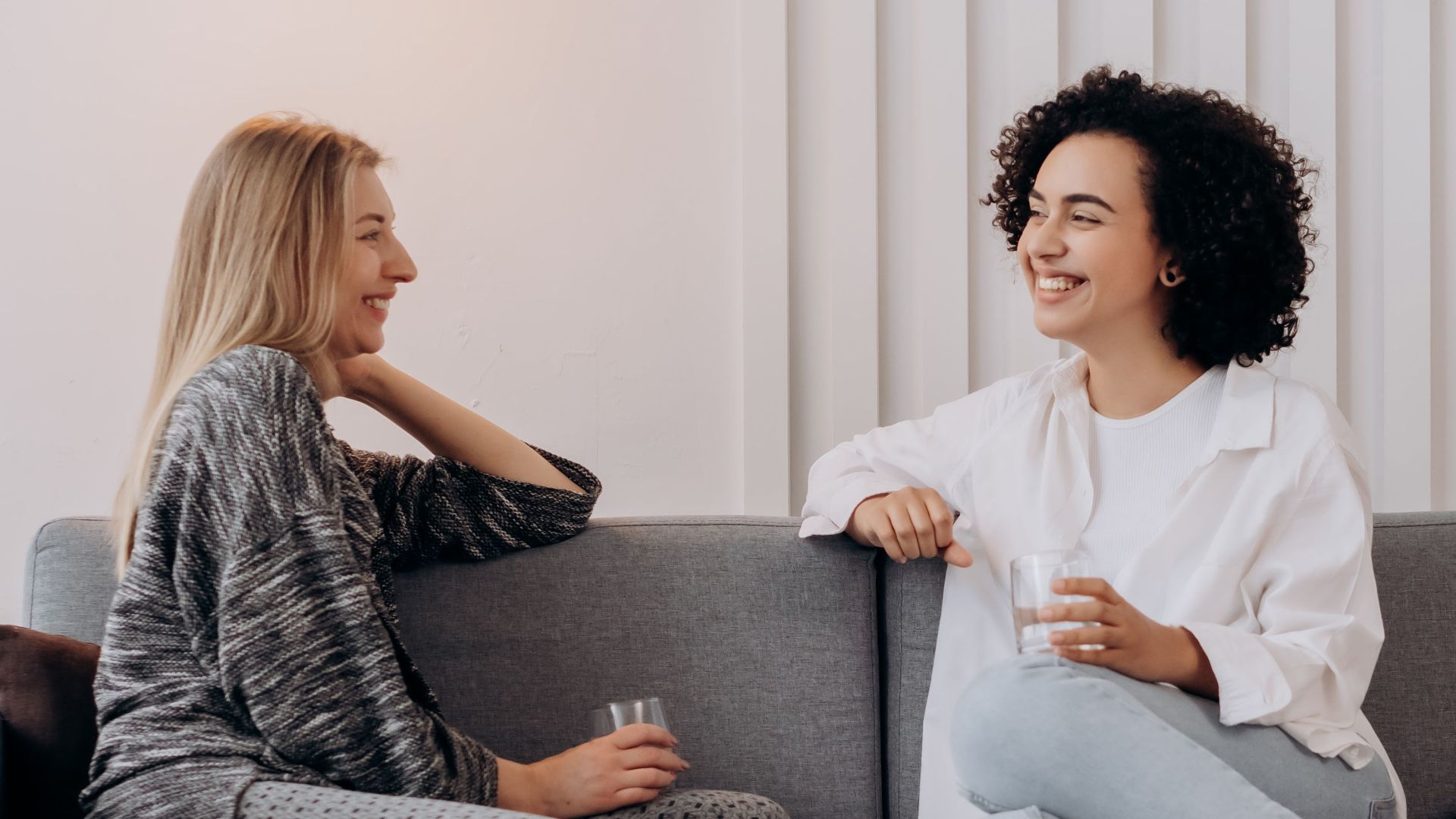 Two women enjoying a relaxed conversation on a modern gray sofa.