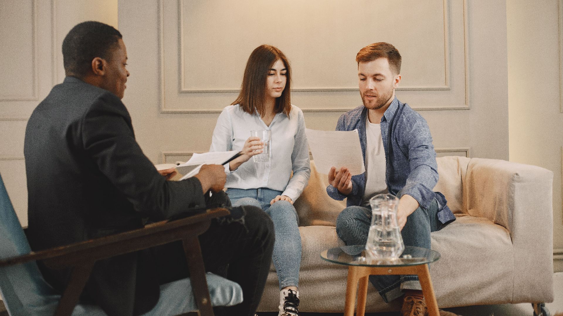 Therapist counseling couple with documents in contemporary office setting.