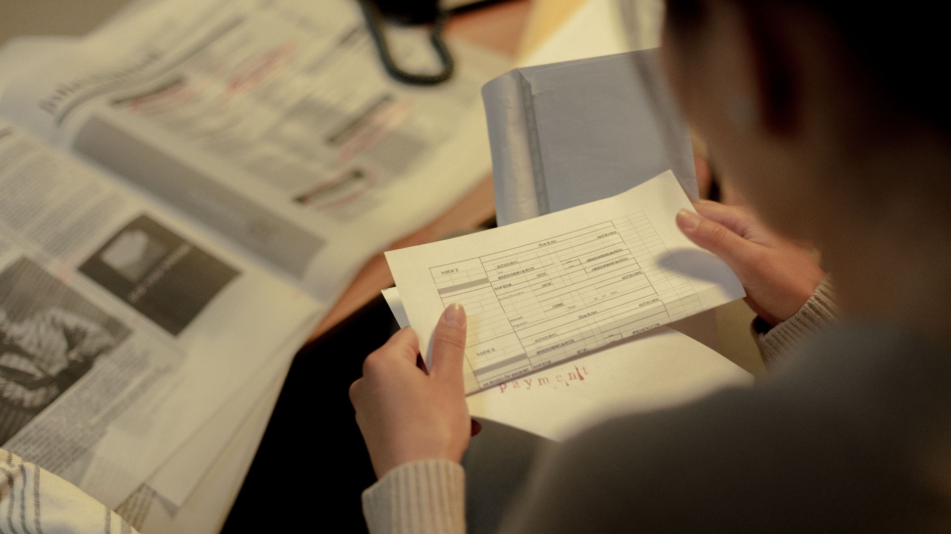 Adult woman reading a questionnaire and job postings indoors at a table, focused and contemplative.