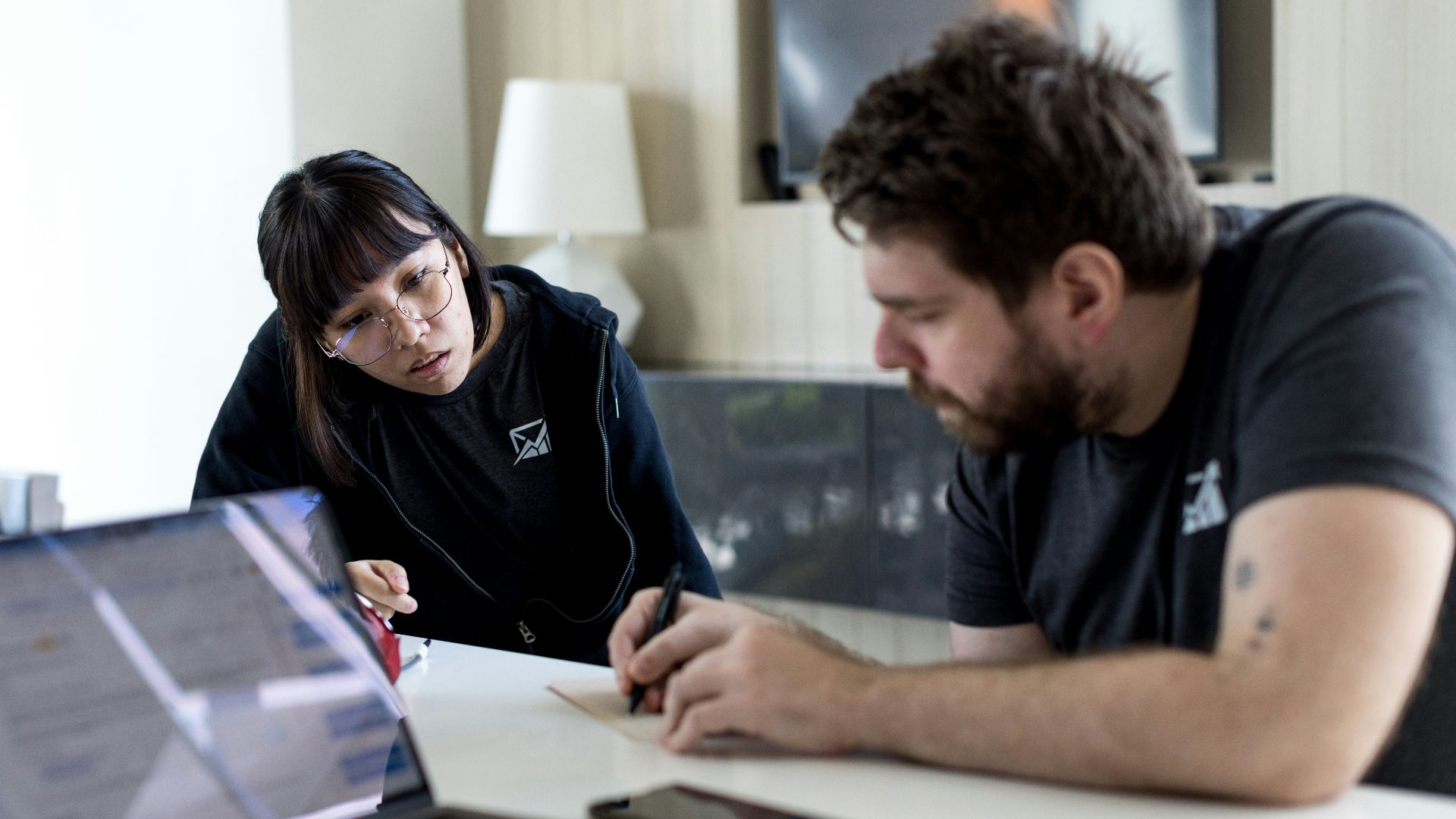 a man and a woman sitting at a table with a laptop
