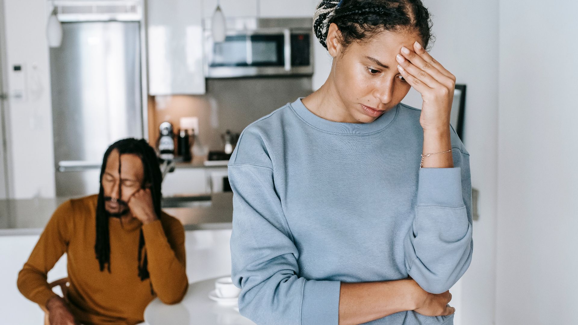 Young African American guy sitting at table and having conflict with lady at home
